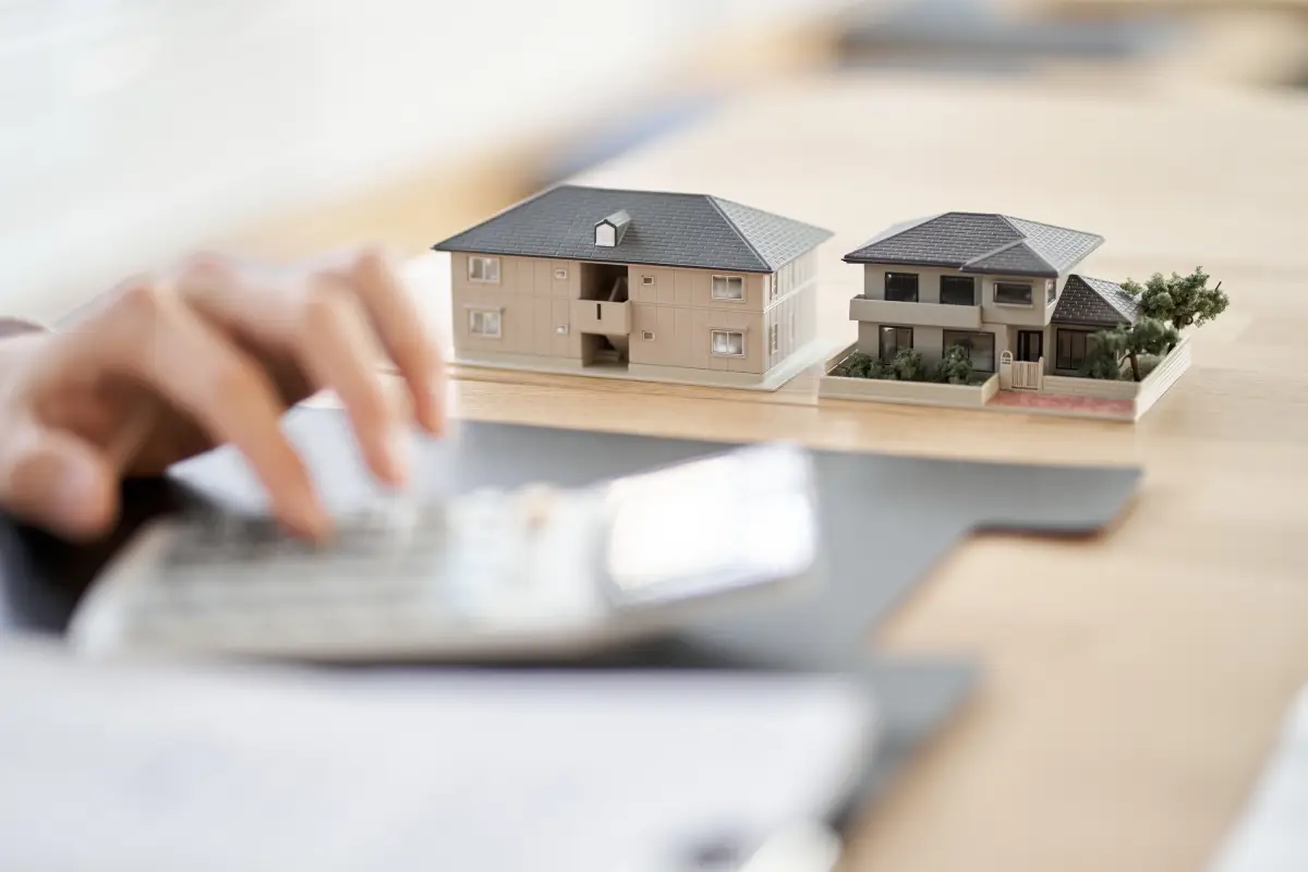 家の模型と電卓を叩く手